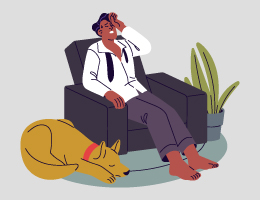 A man leans back in an armchair with a hand to his forehead while his dog sleeps on the floor beside him.