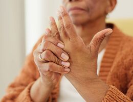 A woman massages one of her hands with the other.