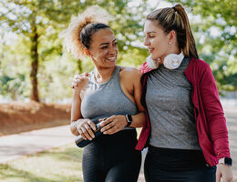 Two women in fitness clothes on a paved walking path.