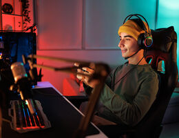 A man in a darkened room plays a game on a computer.